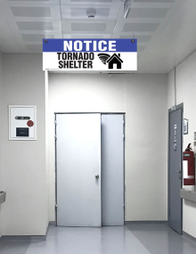 Overhead safety sign reading "Notice Tornado Shelter" with directional indicator, made of 4mm corrugated plastic for drop-ceiling grid hanging.