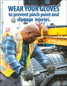 A safety poster featuring a worker in a high-visibility vest and gloves operating heavy equipment. The text reads: "WEAR YOUR GLOVES to prevent pinch point and slippage injuries."