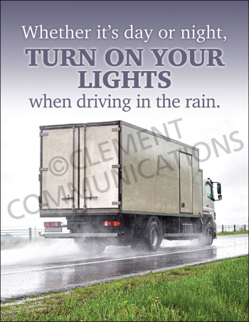A commercial box truck driving on a wet road during a rainstorm with water splashing from the tires, beneath bold text reading: "Whether it's day or night, TURN ON YOUR LIGHTS when driving in the rain."