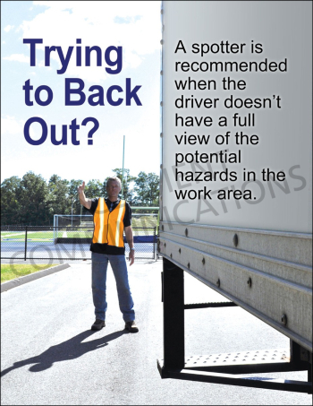 An outdoor industrial work area showing a safety spotter in a high-visibility orange vest guiding a large white delivery truck backing up.